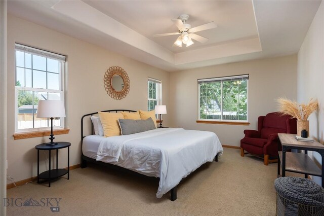 56 Green Belt Dr, Belgrade, MT 59714 - bedroom with baseboards, light carpet, a raised ceiling, and a ceiling fan