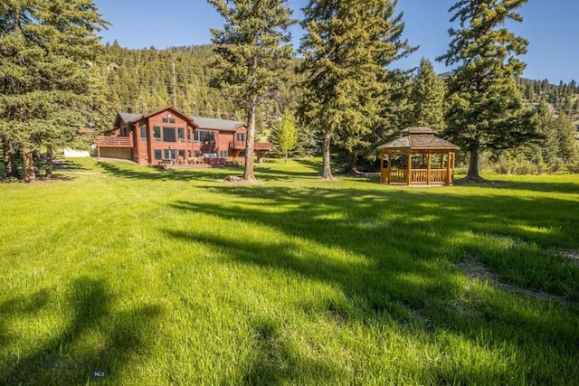 48042 Gallatin Rd, Big Sky, MT 59730 - view of green lawn featuring a gazebo, a forest view, a deck, and a garage