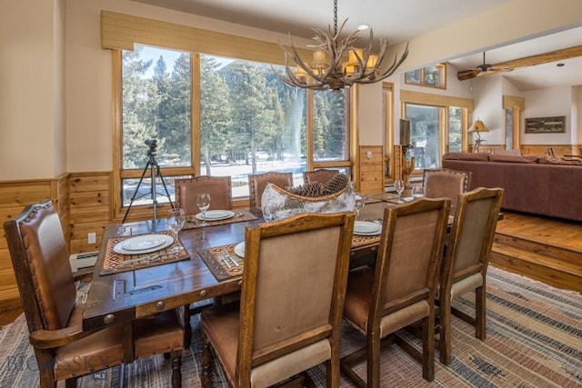 48042 Gallatin Rd, Big Sky, MT 59730 - dining area with a chandelier, a baseboard radiator, a wainscoted wall, plenty of natural light, and wooden walls
