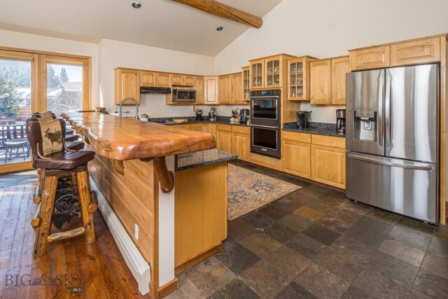 48042 Gallatin Rd, Big Sky, MT 59730 - kitchen with appliances with stainless steel finishes, glass insert cabinets, beamed ceiling, dark stone finish flooring, and a kitchen breakfast bar