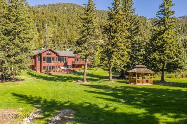 48042 Gallatin Rd, Big Sky, MT 59730 - view of green lawn with a gazebo, a forest view, and a deck