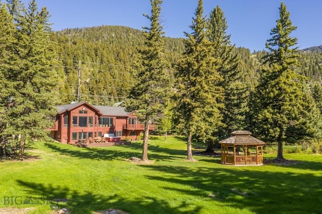 48042 Gallatin Rd, Big Sky, MT 59730 - view of green lawn with a forest view, a gazebo, and a wooden deck