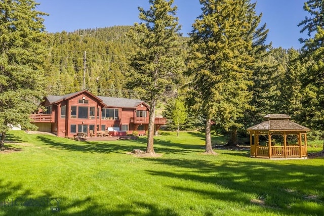 48042 Gallatin Rd, Big Sky, MT 59730 - rear view of house featuring a wooded view, a gazebo, a lawn, and a deck