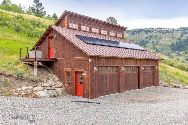 3011 Goose Creek Rd, Bozeman, MT 59715 - view of front of house with roof mounted solar panels, metal roof, driveway, and a detached garage