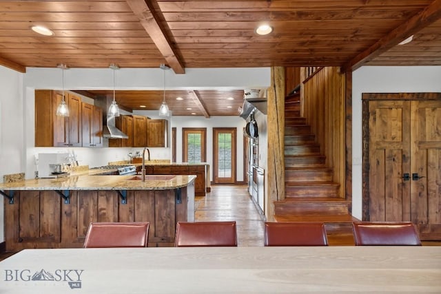 3011 Goose Creek Rd, Bozeman, MT 59715 - kitchen with wood ceiling with exposed beams, a peninsula, light wood-style flooring, light stone countertops, and brown cabinets