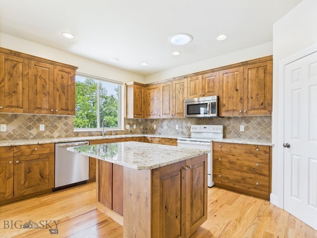3405 W Fieldstone Dr, Bozeman, MT 59715 - kitchen with appliances with stainless steel finishes, brown cabinets, a sink, light stone counters, and light wood finished floors