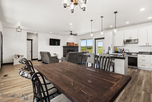30 Blue Stem Way, Three Forks, MT 59752 - dining room with ceiling fan, a warm lit fireplace, recessed lighting, light wood-style floors, and a chandelier