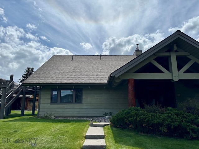 2225 Black Otter Rd Unit 23, Big Sky, MT 59716 - view of front of house with a front yard, a shingled roof, and a chimney