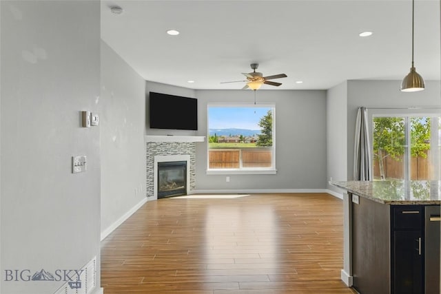 110 Ramshorn Peak Ln, Bozeman, MT 59718 - unfurnished living room featuring wood finished floors, a ceiling fan, healthy amount of natural light, baseboards, and recessed lighting