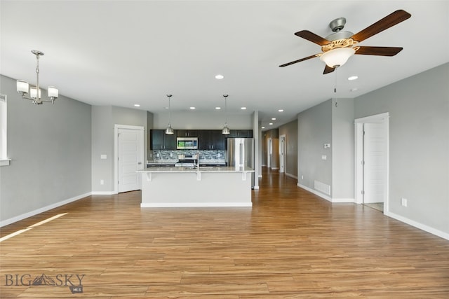 110 Ramshorn Peak Ln, Bozeman, MT 59718 - kitchen featuring appliances with stainless steel finishes, light countertops, open floor plan, light wood finished floors, and recessed lighting