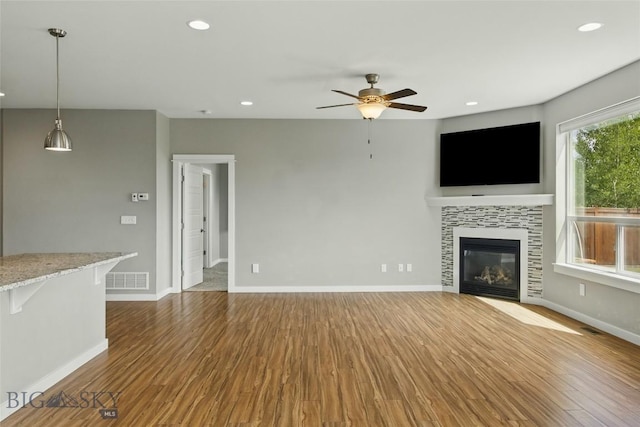 110 Ramshorn Peak Ln, Bozeman, MT 59718 - unfurnished living room with a ceiling fan, wood finished floors, baseboards, a tile fireplace, and recessed lighting