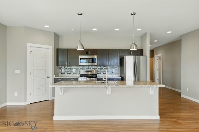 110 Ramshorn Peak Ln, Bozeman, MT 59718 - kitchen featuring appliances with stainless steel finishes, wood finished floors, decorative backsplash, baseboards, and a breakfast bar area