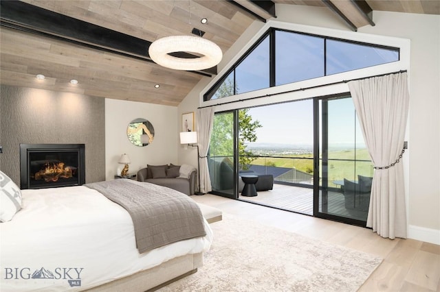 354 Brass Lantern Ct, Bozeman, MT 59715 - bedroom featuring access to exterior, beam ceiling, wood finished floors, high vaulted ceiling, and a warm lit fireplace