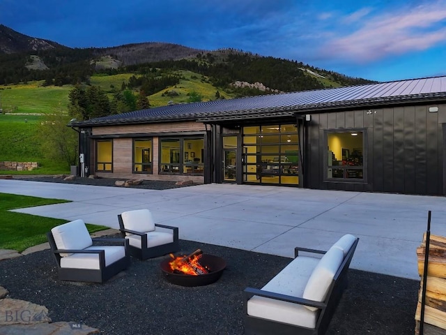 354 Brass Lantern Ct, Bozeman, MT 59715 - back of property featuring a mountain view, board and batten siding, a fire pit, and metal roof