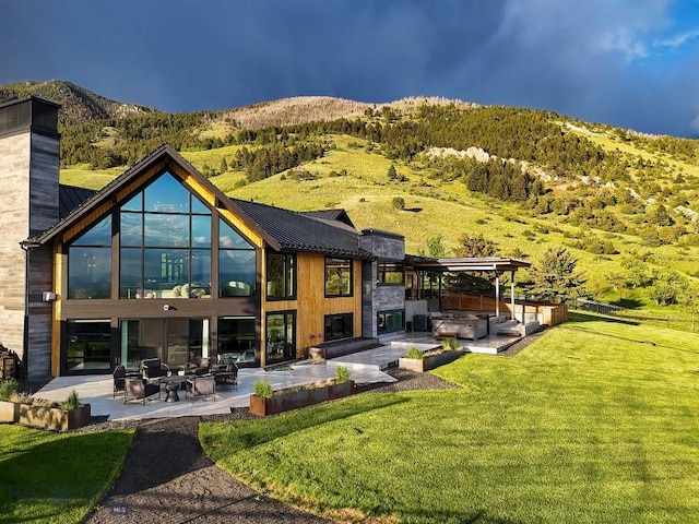 354 Brass Lantern Ct, Bozeman, MT 59715 - rear view of property with a patio area, a chimney, a lawn, an outdoor hangout area, and a mountain view