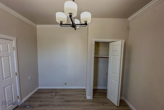 211 W Main St, East Helena, MT 59635 - unfurnished bedroom with crown molding, a chandelier, wood finished floors, and a closet