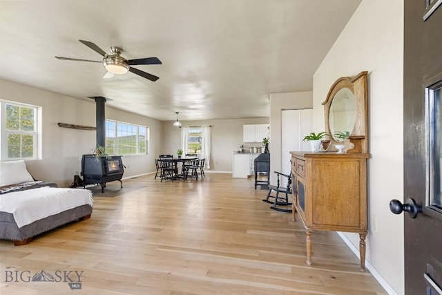 251 Price Rd, Three Forks, MT 59752 - living area with light wood-style floors, a wood stove, a ceiling fan, and baseboards