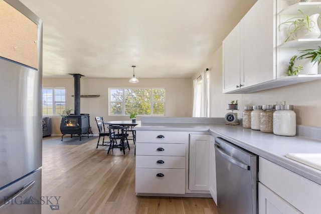 251 Price Rd, Three Forks, MT 59752 - kitchen with stainless steel appliances, white cabinetry, light wood finished floors, a wood stove, and light countertops