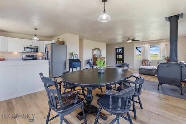 251 Price Rd, Three Forks, MT 59752 - dining area with light wood-style floors, a ceiling fan, and a wood stove