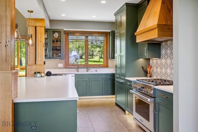 2594 Star Ridge Rd, Bozeman, MT 59715 - kitchen with green cabinetry, custom range hood, high end stainless steel range, backsplash, and light countertops