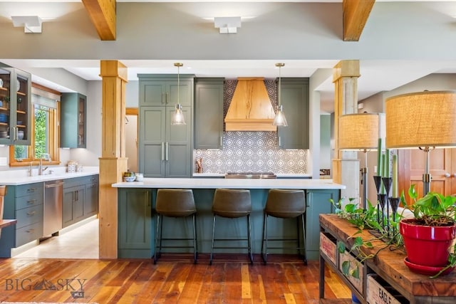 2594 Star Ridge Rd, Bozeman, MT 59715 - kitchen featuring custom range hood, ornate columns, light countertops, tasteful backsplash, and stainless steel dishwasher