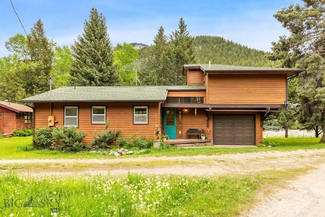 140 Luhn, Gallatin Gateway, MT 59730 - view of front facade with dirt driveway, an attached garage, a mountain view, and a view of trees