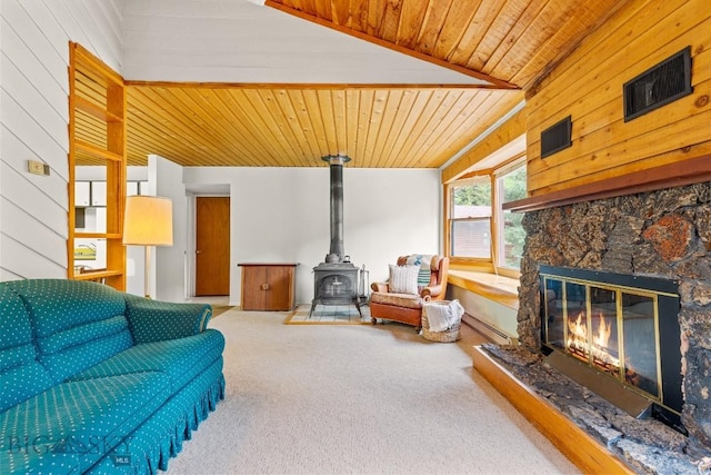 140 Luhn, Gallatin Gateway, MT 59730 - carpeted living area featuring a wood stove, a fireplace, wooden ceiling, and wood walls