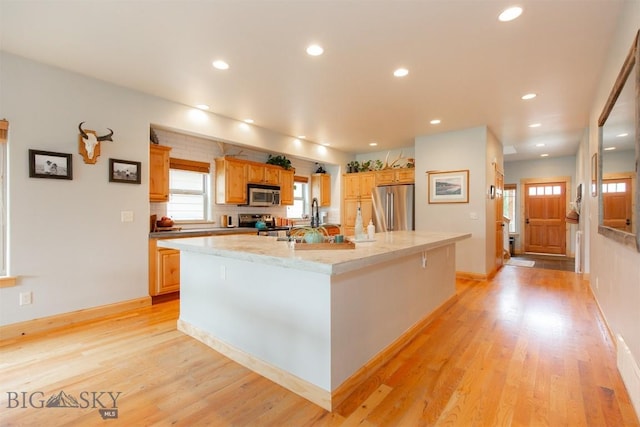 975 Jessie Way, Bozeman, MT 59715 - kitchen featuring appliances with stainless steel finishes, a spacious island, recessed lighting, light wood-style floors, and a sink