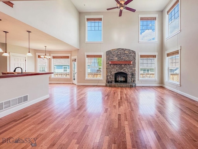 2475 Rose St, Bozeman, MT 59718 - unfurnished living room featuring a towering ceiling, hardwood / wood-style floors, a stone fireplace, ceiling fan, and baseboards