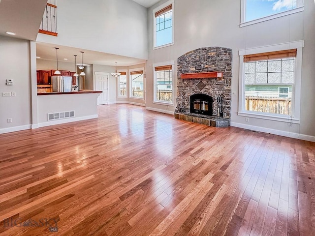 2475 Rose St, Bozeman, MT 59718 - unfurnished living room featuring a high ceiling, light wood finished floors, a chandelier, baseboards, and a stone fireplace