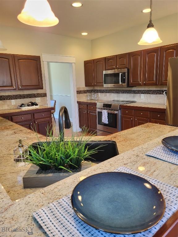 2475 Rose St, Bozeman, MT 59718 - kitchen with stainless steel appliances, decorative backsplash, pendant lighting, light stone counters, and recessed lighting
