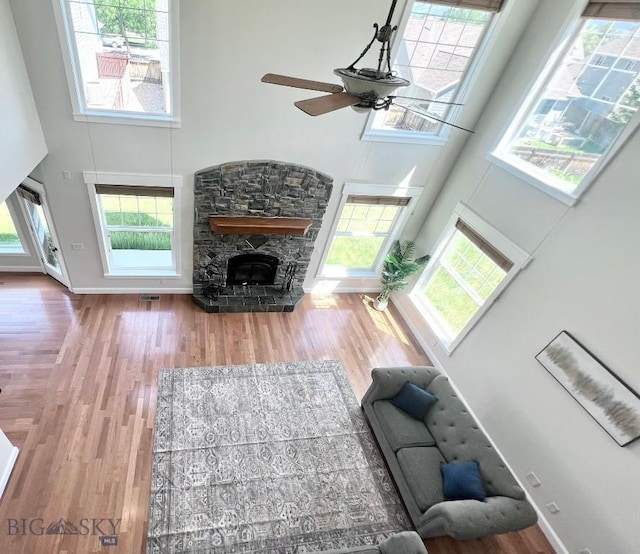 2475 Rose St, Bozeman, MT 59718 - living room with a high ceiling, a stone fireplace, ceiling fan, wood finished floors, and plenty of natural light
