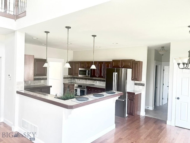 2475 Rose St, Bozeman, MT 59718 - kitchen featuring appliances with stainless steel finishes, light wood-style flooring, dark brown cabinetry, and backsplash