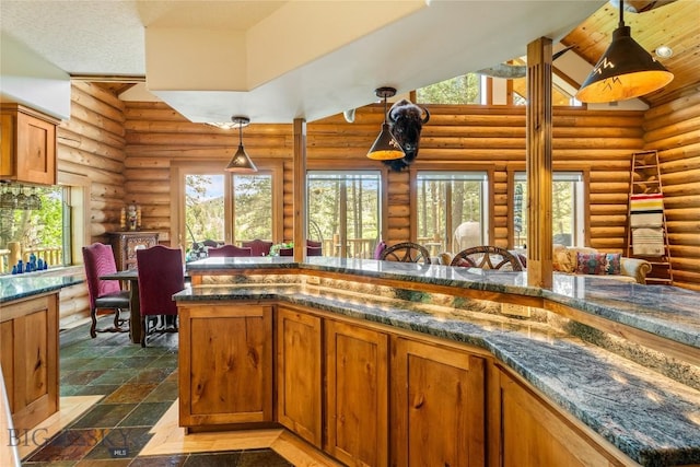 1561/1563 Colorado Gulch Dr, Helena, MT 59601 - kitchen featuring log walls, plenty of natural light, brown cabinets, high vaulted ceiling, and hanging light fixtures