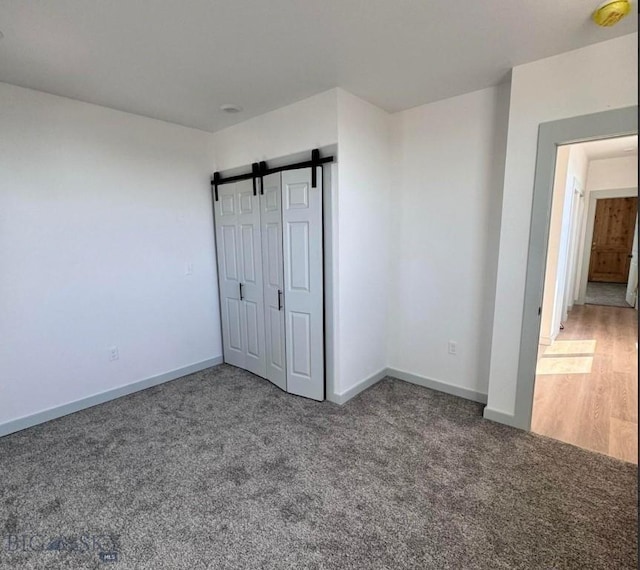 823 S Main, Butte, MT 59701 - unfurnished bedroom featuring carpet, baseboards, and a barn door