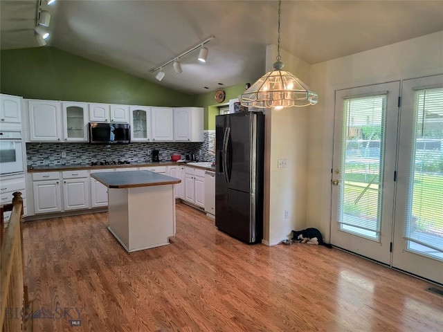1006 E Missoula, Belgrade, MT 59714 - kitchen with black appliances, track lighting, vaulted ceiling, healthy amount of natural light, and wood finished floors