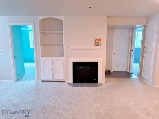 1006 E Missoula, Belgrade, MT 59714 - unfurnished living room featuring carpet flooring, built in features, a fireplace with flush hearth, and baseboards