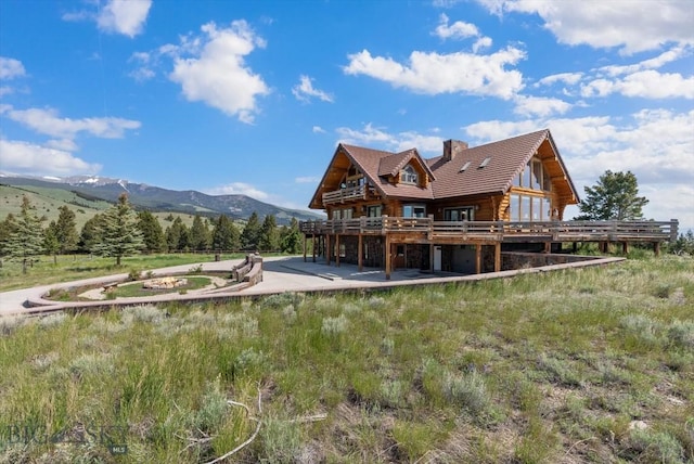 1380 Glacier View Dr, Deer Lodge, MT 59722 - rear view of house with a deck with mountain view, a chimney, and log exterior