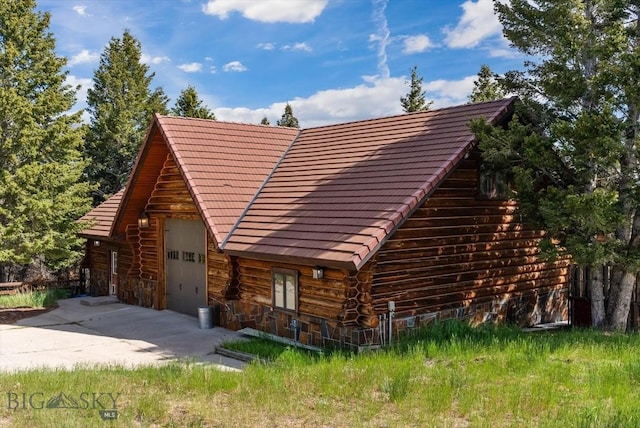 1380 Glacier View Dr, Deer Lodge, MT 59722 - log cabin with a garage, a tiled roof, and driveway
