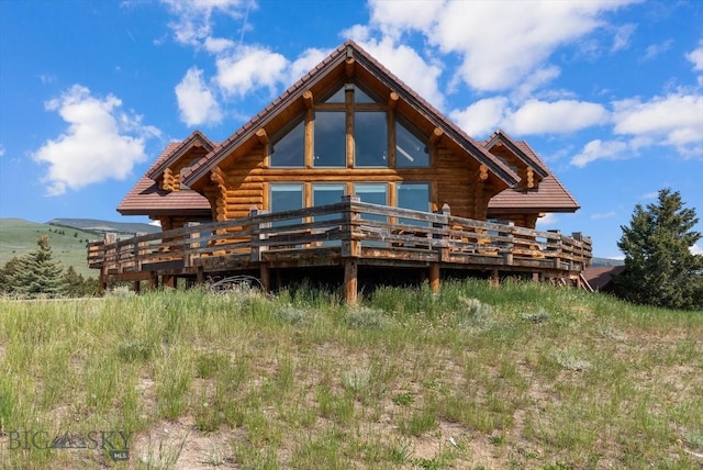 1380 Glacier View Dr, Deer Lodge, MT 59722 - back of property with log siding, a deck with mountain view, and a tiled roof