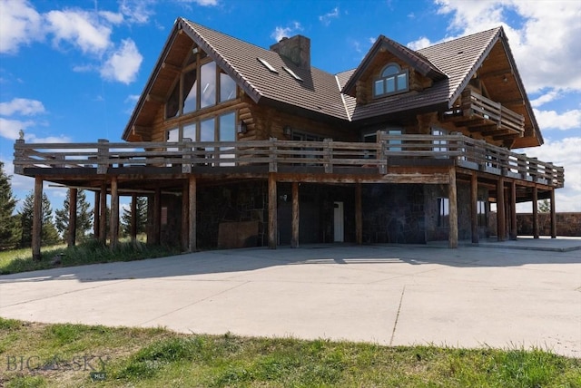 1380 Glacier View Dr, Deer Lodge, MT 59722 - view of property exterior featuring a deck, a chimney, log siding, concrete driveway, and stone siding