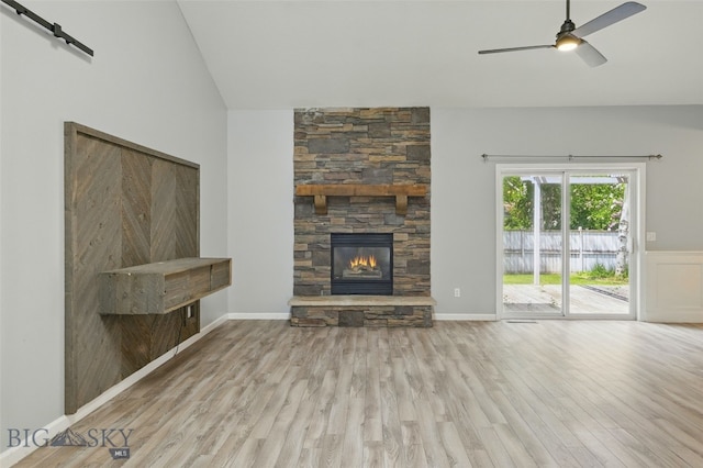 1205 Brentwood, Bozeman, MT 59718 - unfurnished living room featuring a barn door, wood finished floors, lofted ceiling, a stone fireplace, and ceiling fan
