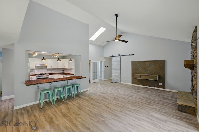 1205 Brentwood, Bozeman, MT 59718 - living room featuring a barn door, high vaulted ceiling, a ceiling fan, light wood-type flooring, and a skylight