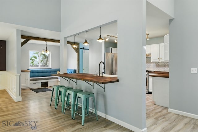 1205 Brentwood, Bozeman, MT 59718 - kitchen featuring wood counters, stainless steel appliances, a kitchen bar, and light wood-type flooring