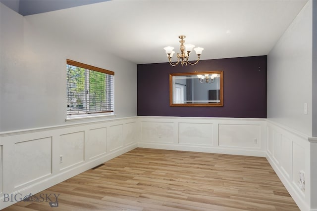 1205 Brentwood, Bozeman, MT 59718 - unfurnished dining area featuring a chandelier, light wood finished floors, wainscoting, and a decorative wall