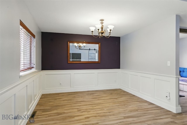 1205 Brentwood, Bozeman, MT 59718 - unfurnished dining area featuring a chandelier, light wood finished floors, a decorative wall, and wainscoting