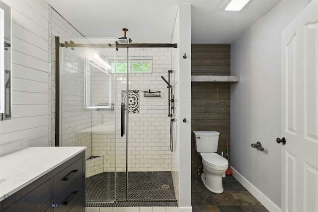 1205 Brentwood, Bozeman, MT 59718 - bathroom featuring toilet, vanity, a shower stall, baseboards, and stone finish floors