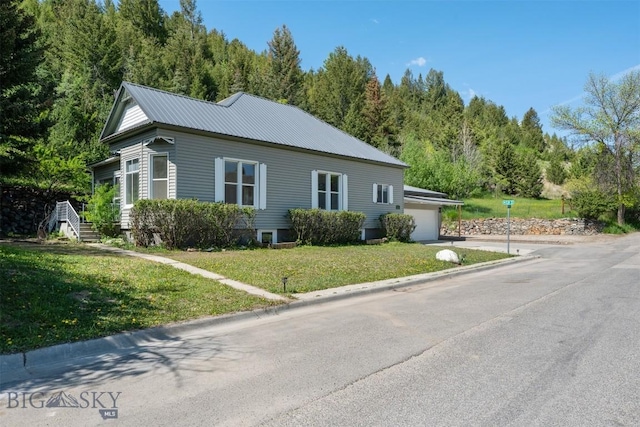 411 W 7th St, Anaconda, MT 59711 - view of property exterior with a lawn, an attached garage, concrete driveway, metal roof, and a view of trees