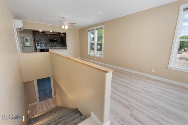 411 W 7th St, Anaconda, MT 59711 - staircase featuring wood finished floors, baseboards, ceiling fan, and a wall mounted air conditioner
