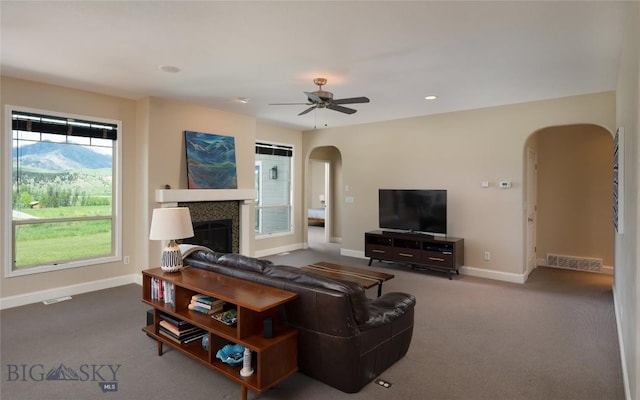 15 Blue Grouse Ct, Bozeman, MT 59715 - living area featuring arched walkways, baseboards, carpet, ceiling fan, and a tile fireplace